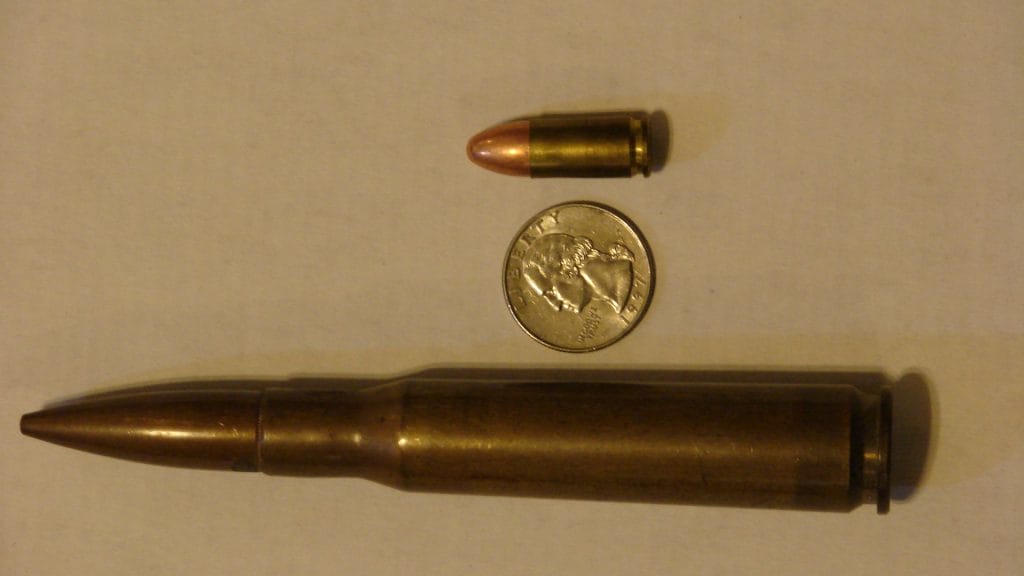 Image of a .50 BMG besides a penny and a 9mm bullet