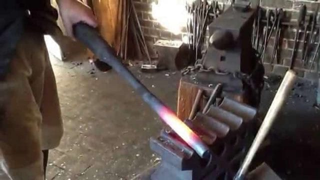 man forging the barrel of an ar15 in his work shed red hot