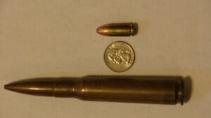 Image of a Browning Machine Gun .50 BMG bullet besides a penny and a 9mm bullet