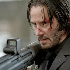 Keanu Reeves playing John Wick holding a shotgun