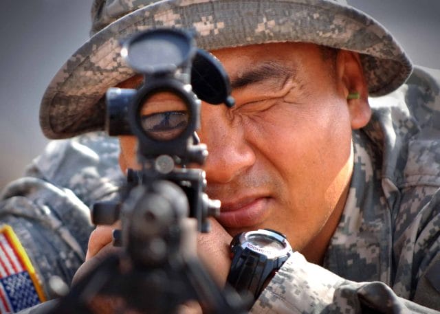 Army sharpshooter aiming his rifle scope