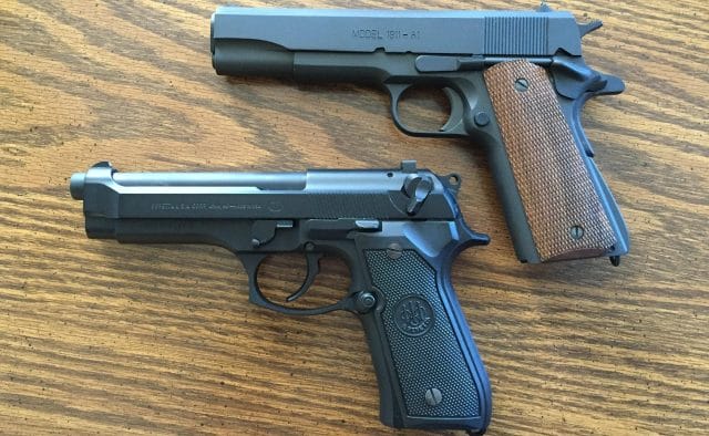 A Beretta M9 and a 1911 laying side by side 