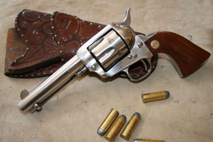 A Colt Single Action Army revolver next to 45 Colt cartridges and holster